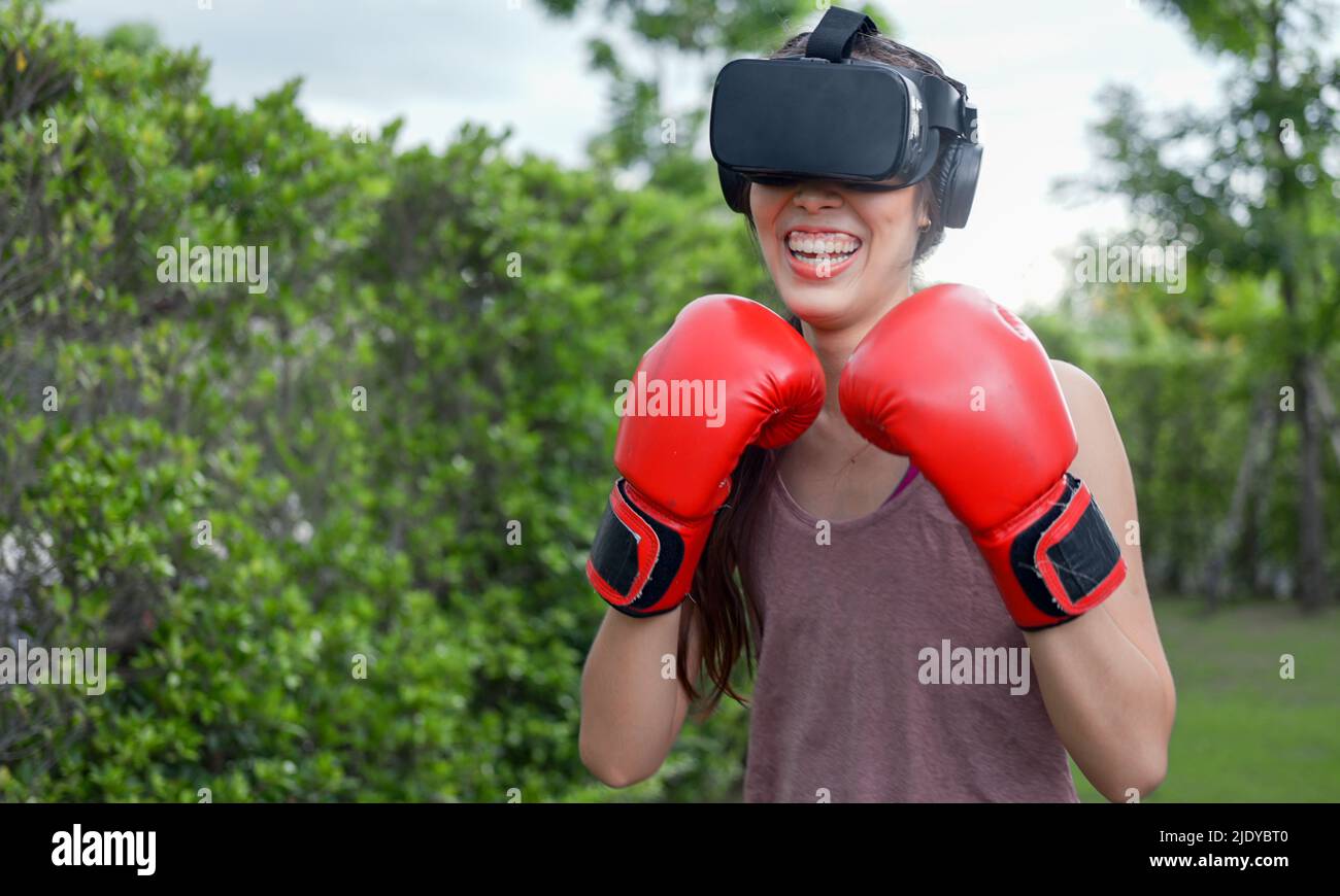 Young female wearing VR headset for working out boxing, aerobic training for boxing punch in virtual reality in simulation world. Stock Photo