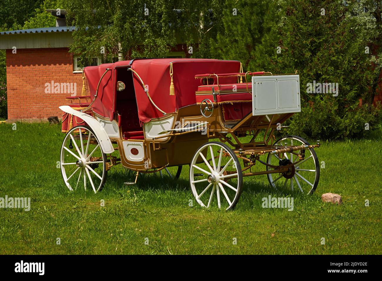 A vintage carriage is standing on the lawn. Without horses Stock Photo