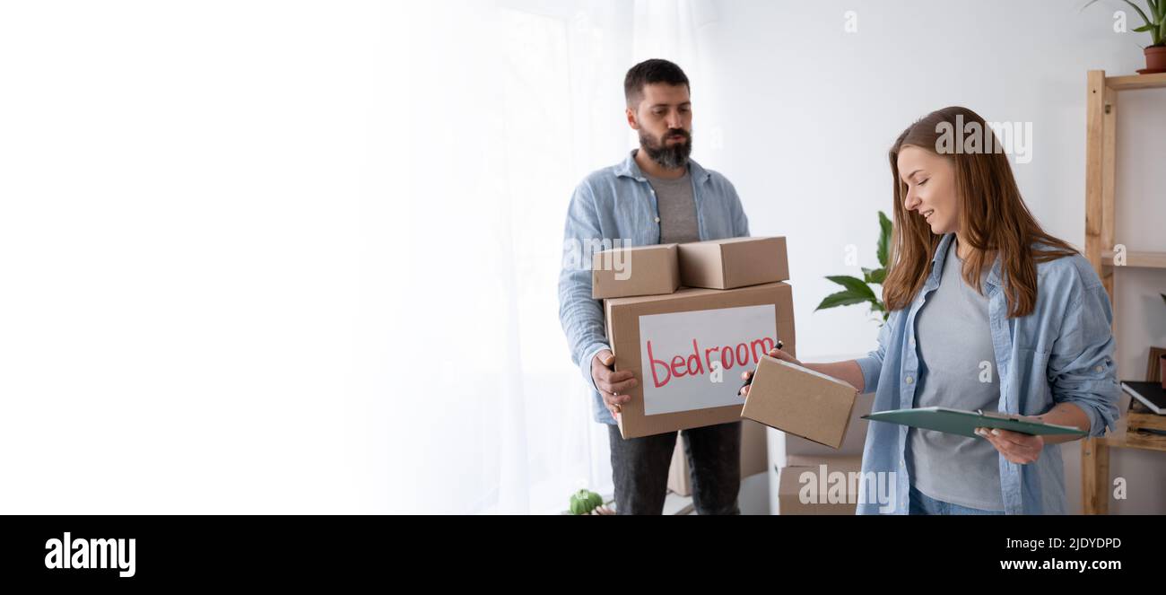 woman writing and checking list of cardoard box when her boyfriend