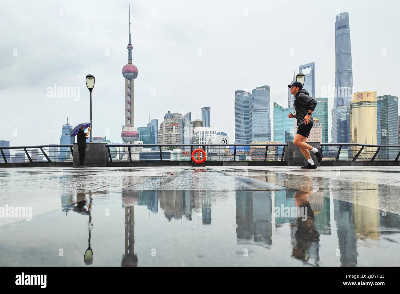 SHANGHAI, CHINA - JUNE 24, 2022 - A tourist holds an umbrella as he passes the Bund in the rain on June 24, 2022 in Shanghai, China. Stock Photo