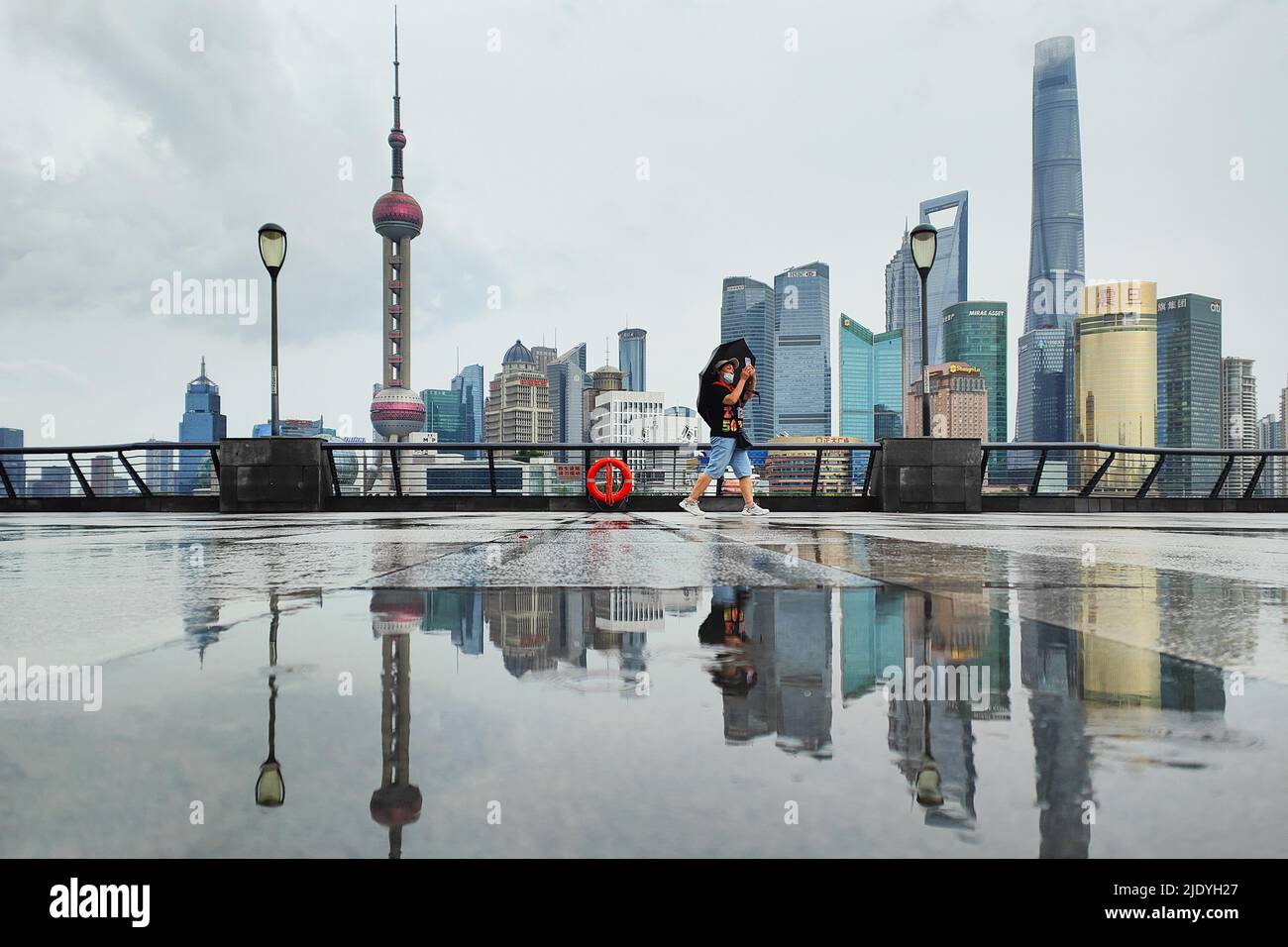 SHANGHAI, CHINA - JUNE 24, 2022 - A tourist holds an umbrella as he passes the Bund in the rain on June 24, 2022 in Shanghai, China. Stock Photo