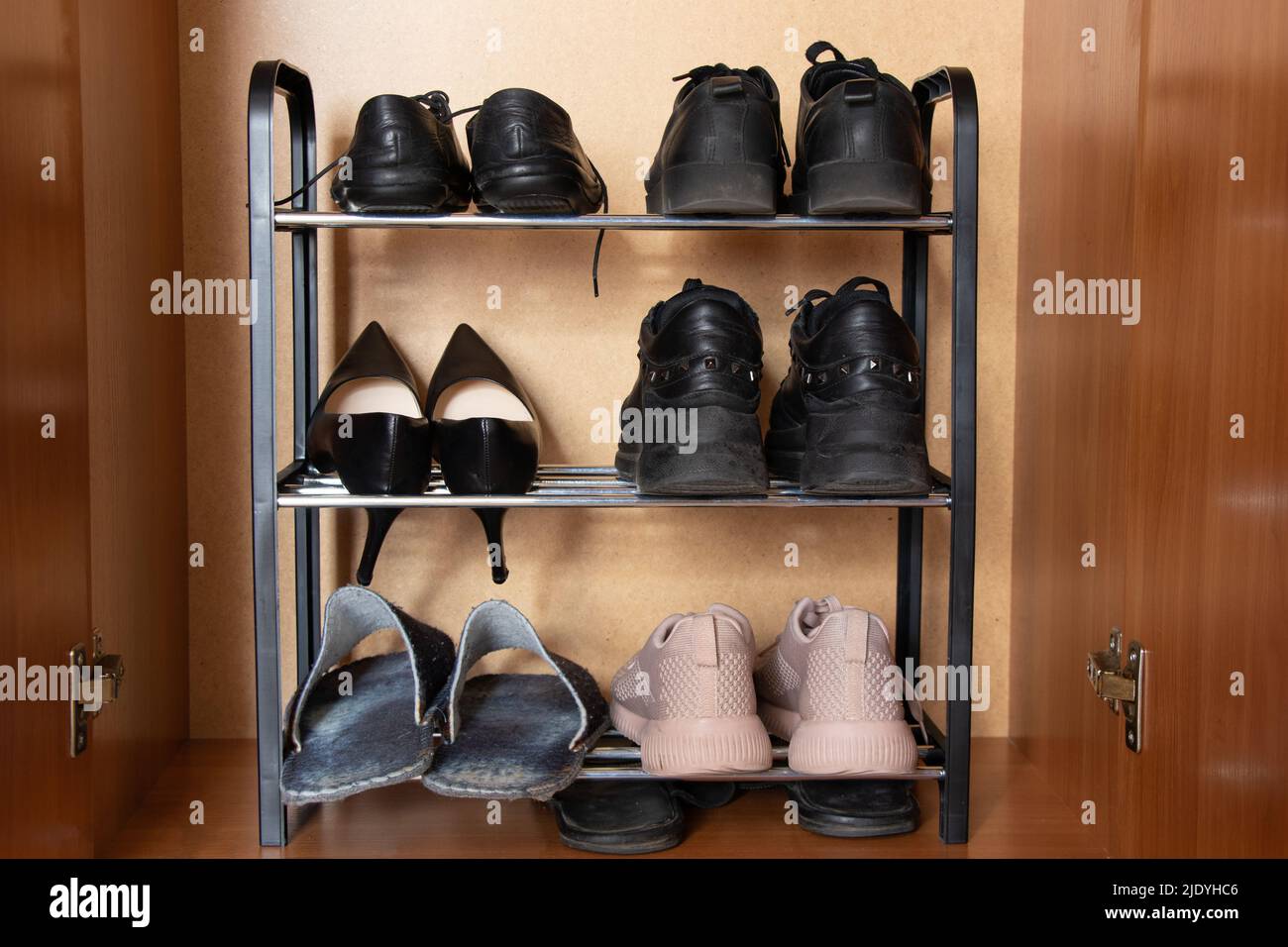 A shelf with shoes in the closet, sneakers, sneakers and shoes are on the shelf in the hallway, women's worn shoes, a pair of old shoes Stock Photo