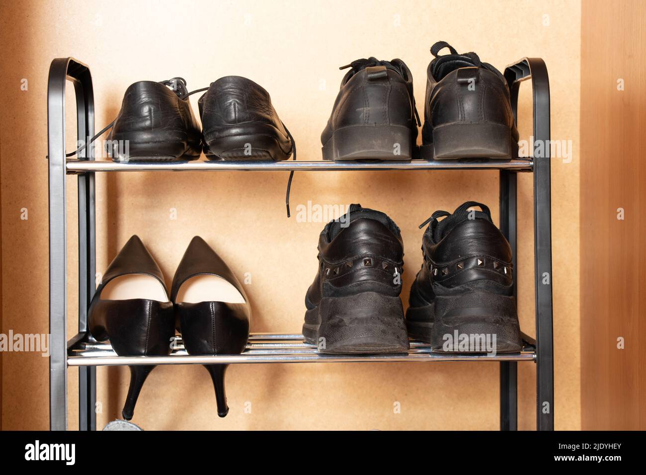 A shelf with shoes in the closet, sneakers, sneakers and shoes are on the shelf in the hallway, women's worn shoes, a pair of old shoes Stock Photo