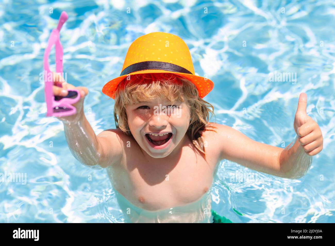 Kid boy in swimming pool on inflatable ring. Children swim with orange float. Water toy, healthy