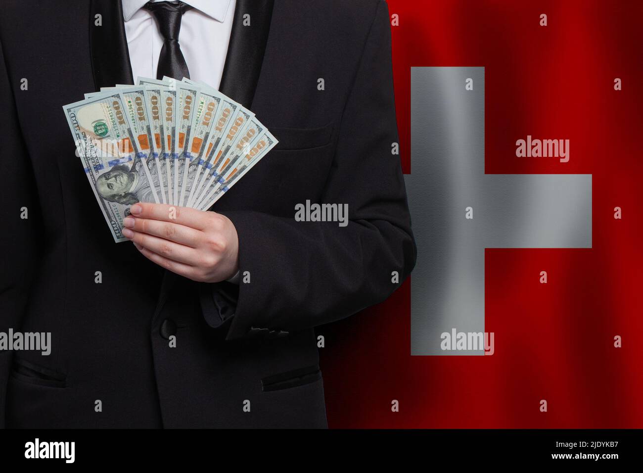 Swiss business man with 100 US dollar bills money banknotes against flag of Switzerland background Stock Photo