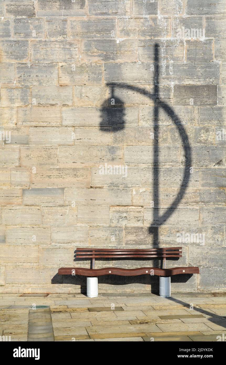 The bench and the shadow. The street light shadow almost looks like a musical note. Stock Photo