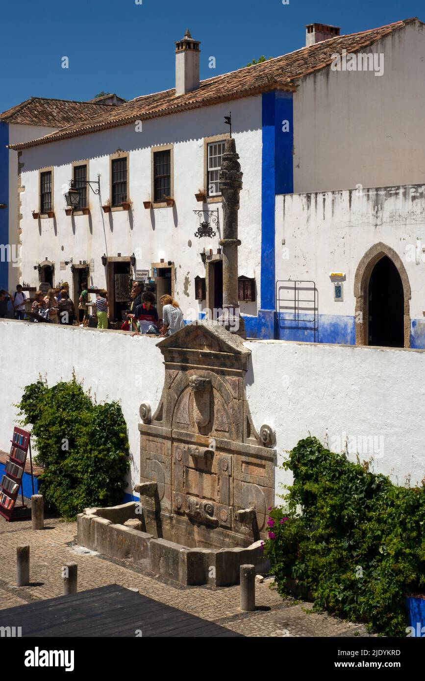 A pillory sculpted in the 1400s and a Mannerist fountain commissioned in 1575 by Queen Catherine of Austria, wife of Portuguese King Joao III: symbols of civic autonomy and royal benevolence in Praça de Santa Maria, the main square of historic Óbidos in the Centro region, Portugal. Stock Photo