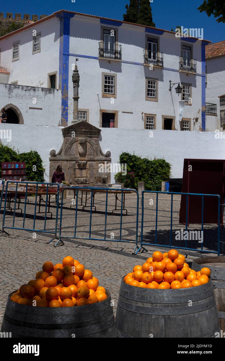 Time for refreshment on a hot summer morning ... ripe juicy oranges ready to be pressed into cooling drinks displayed in Praça de Santa Maria, the paved main square of the showpiece medieval walled town of Óbidos, Centro, Portugal. Stock Photo