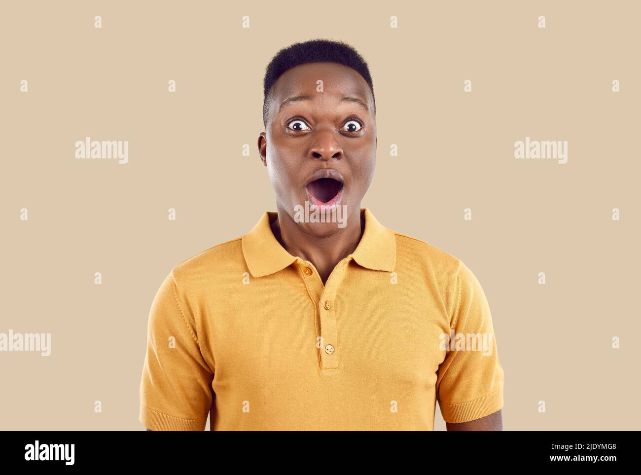 Amazed Frican American man looks at camera with shocked expression on beige background. Stock Photo