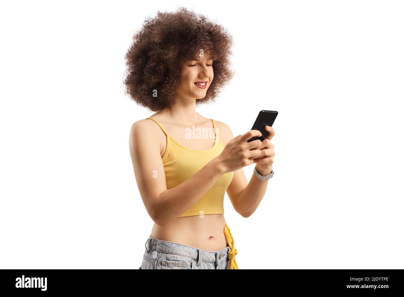 Young caucasian woman with afro hairstyle using a smartphone and smiling isolated on white background Stock Photo