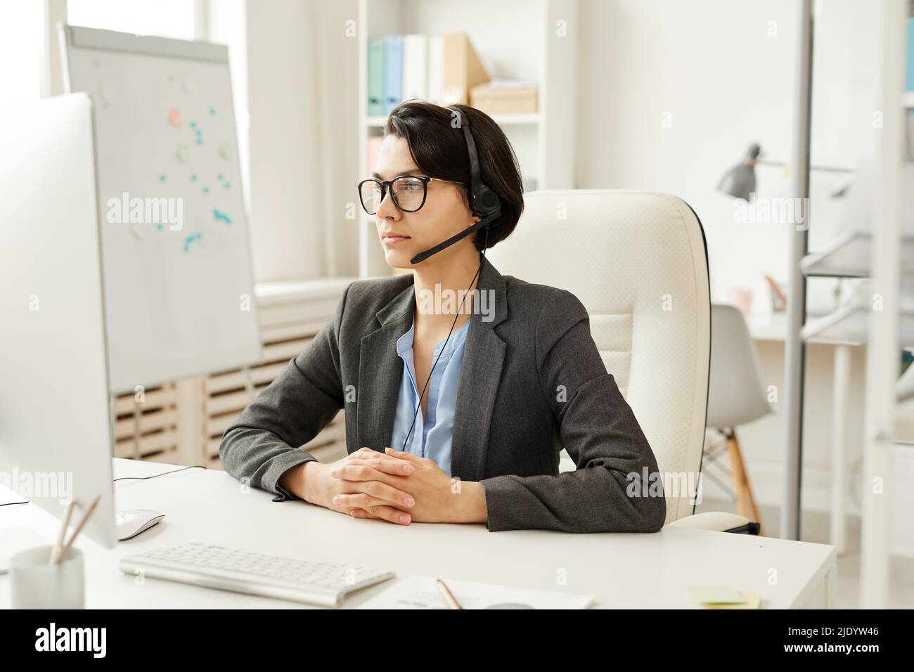 Serious busy young female call center operator in hands-free device ...