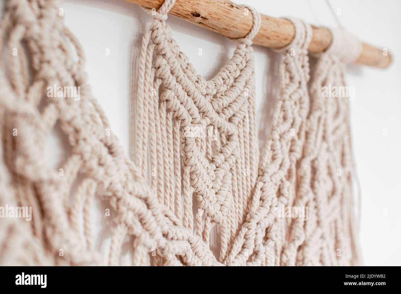 Wall decor in the style of weaving macrame handmade from beige natural  threads on a white background Stock Photo - Alamy