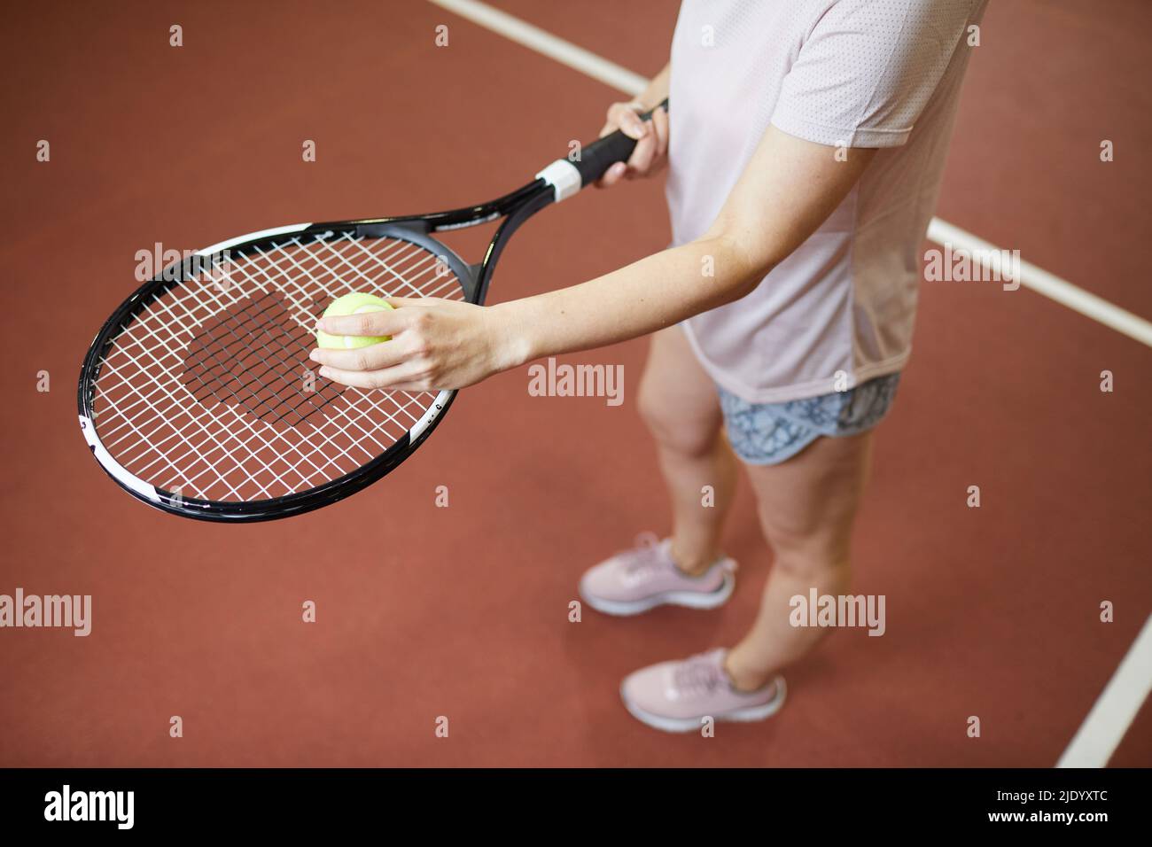 Above view of female tennis player standing on court and throwing ball