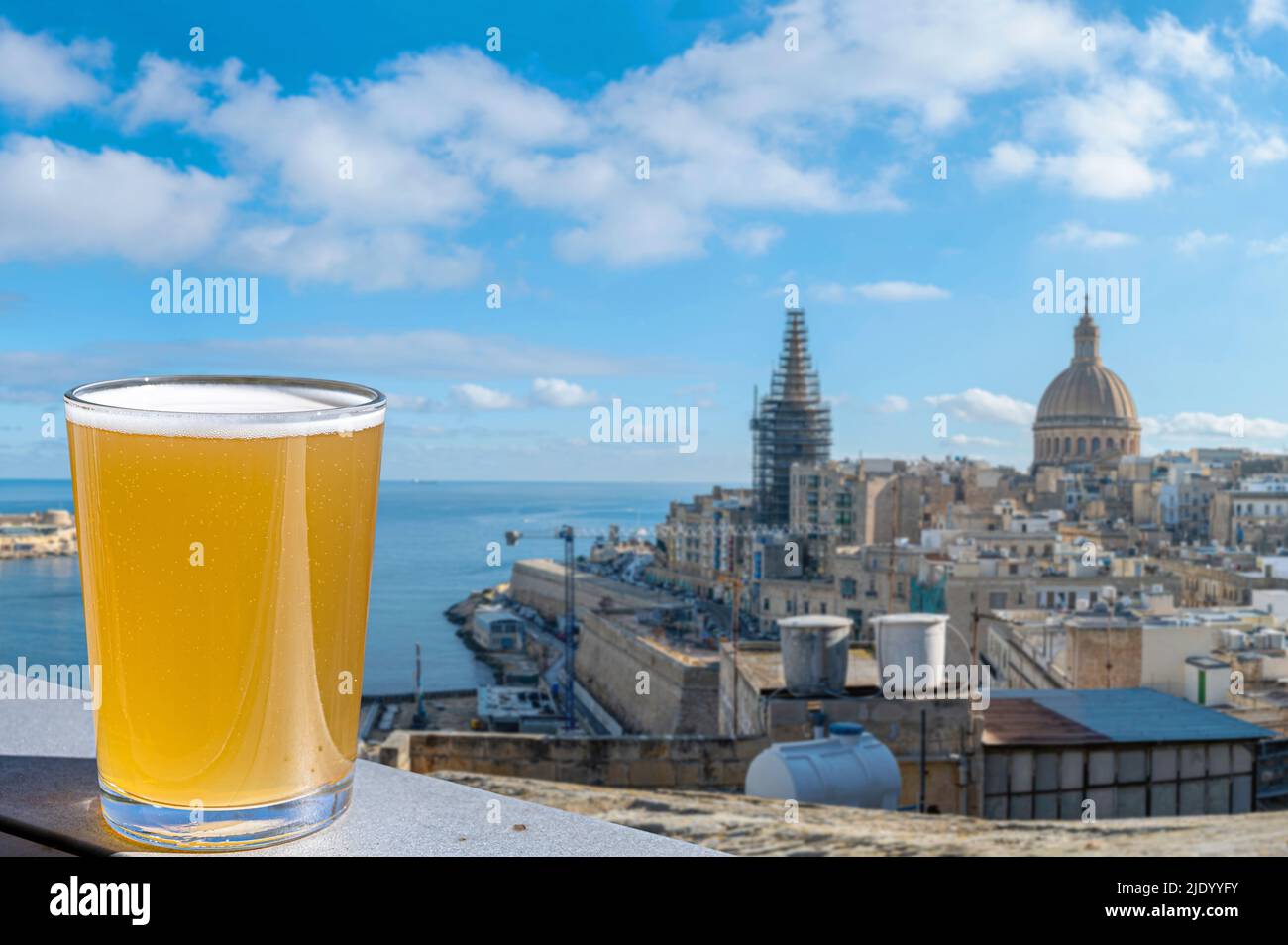 Glass of light beer with view of Valletta old town and harbor in Valletta, Malta. Stock Photo