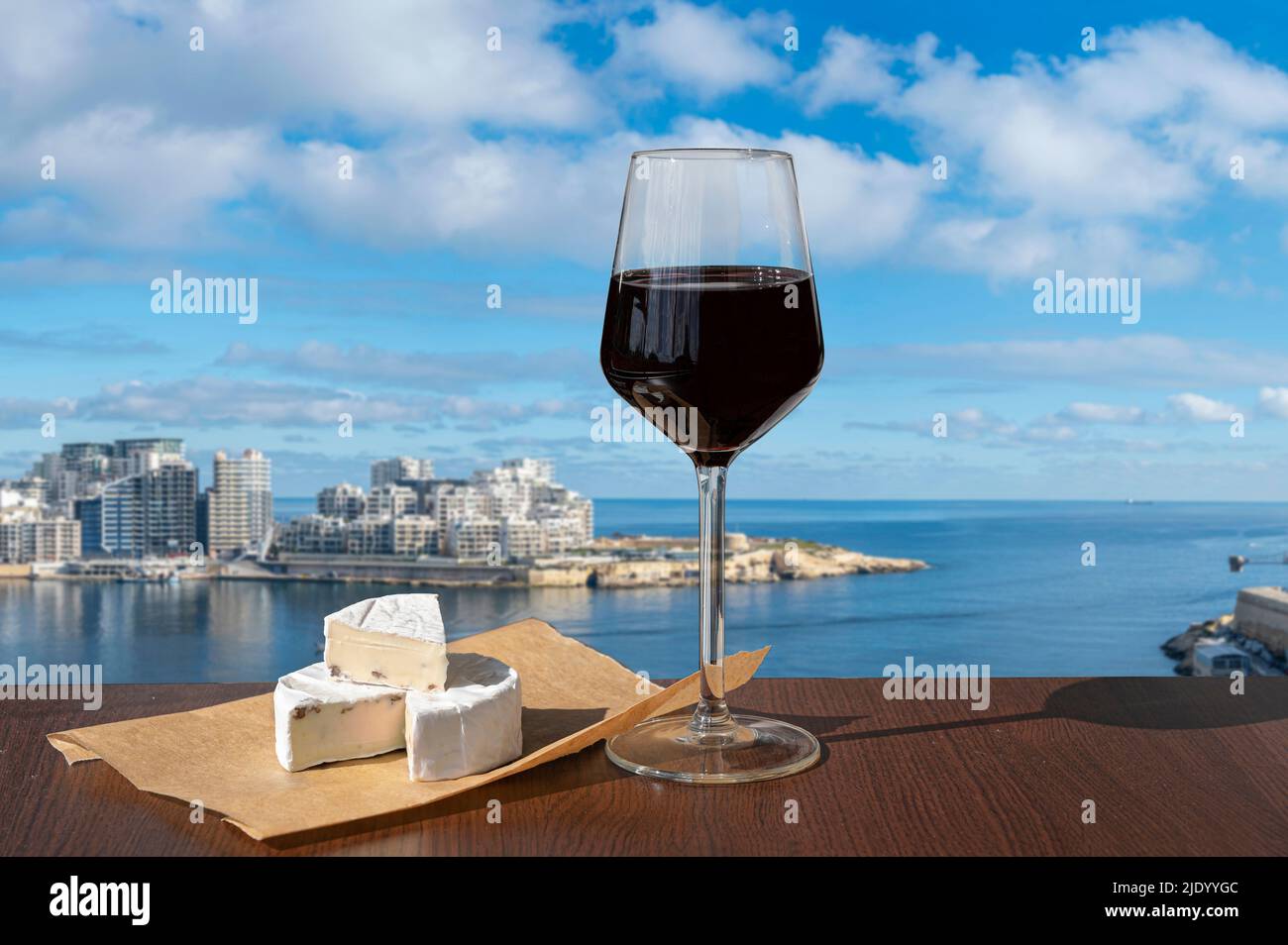 Glass of red wine with cheese with view of Sliema town and harbor. Photo taken from  Valletta, Malta. Stock Photo
