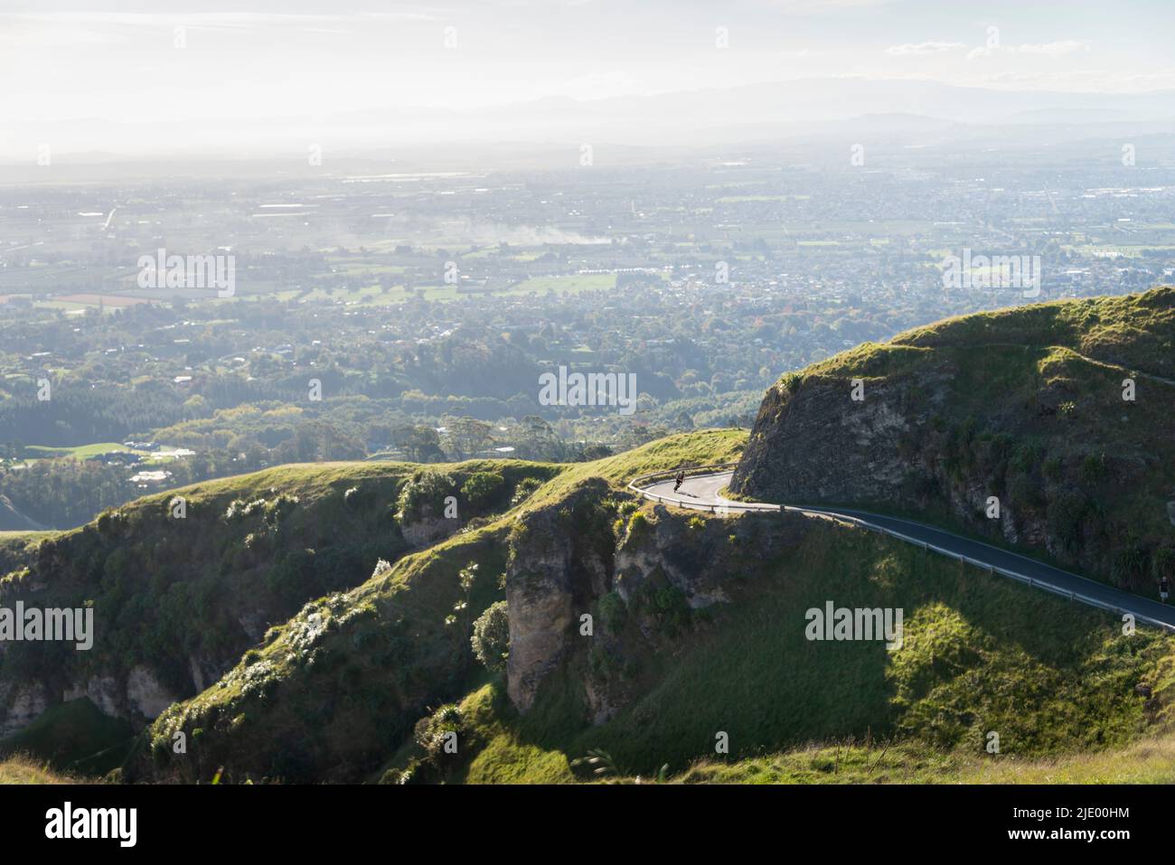 Panorama view of a cyclist riding down the winding road from Te Mata Peak, Hawke’s Bay. Stock Photo