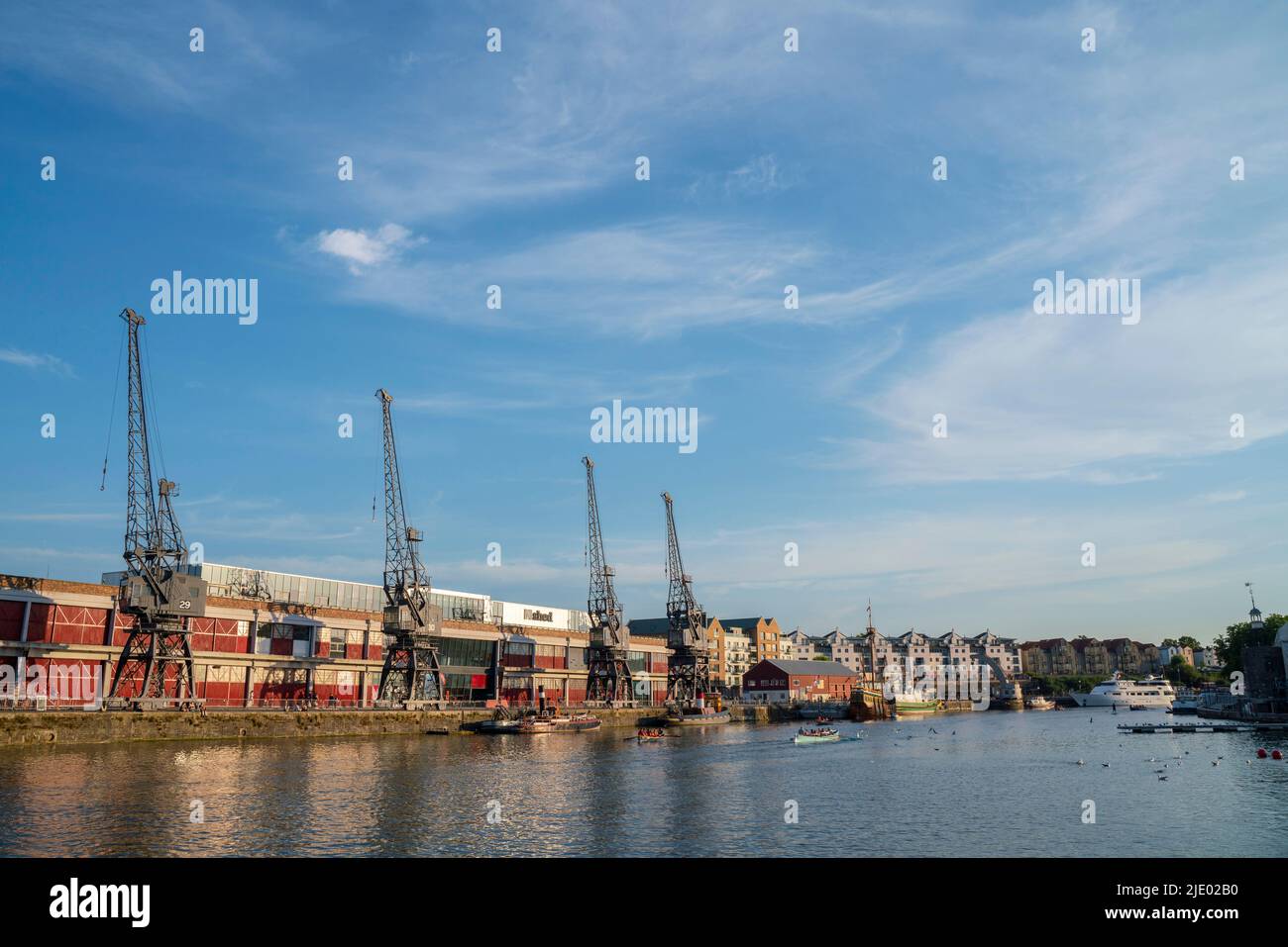 Cranes, rowing boats, and the mShed in the floating harbour harbourside area of Bristol on a sunny summer evening. Stock Photo