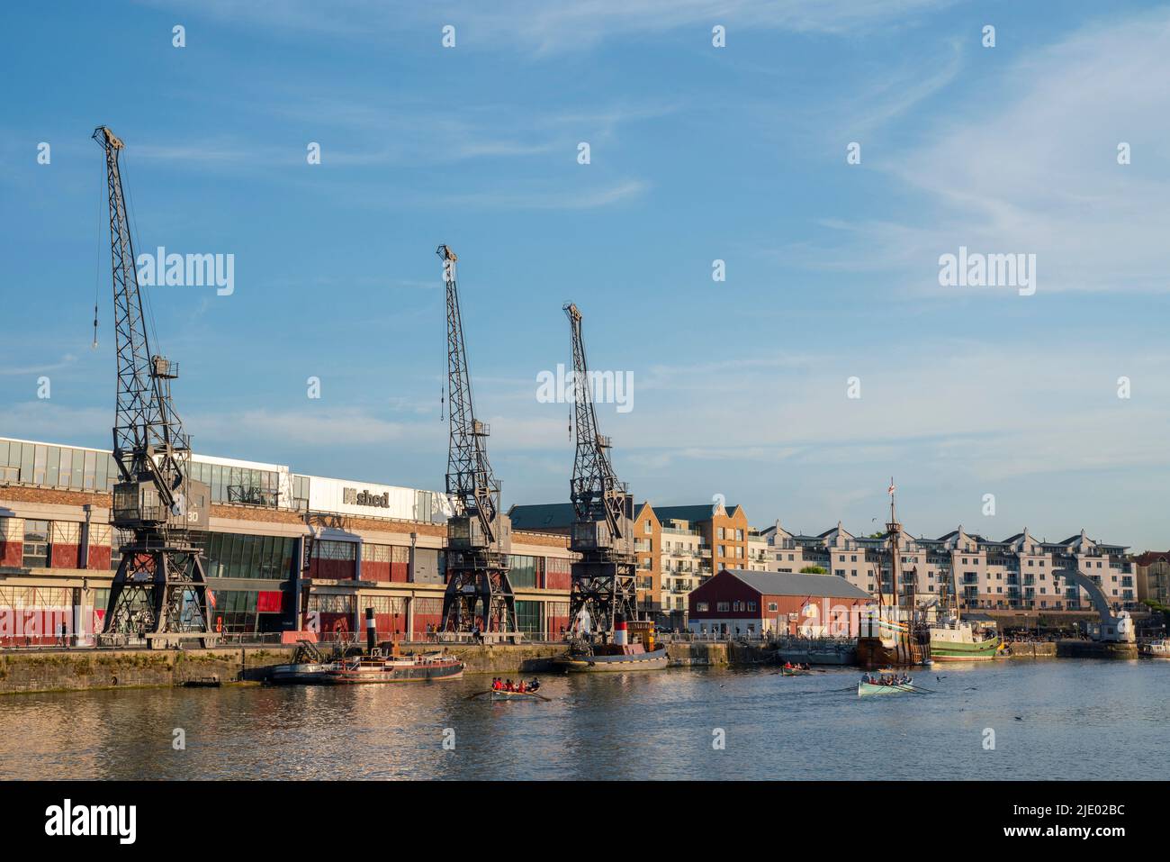 Cranes, rowing boats, and the mShed in the floating harbour harbourside area of Bristol on a sunny summer evening. Stock Photo