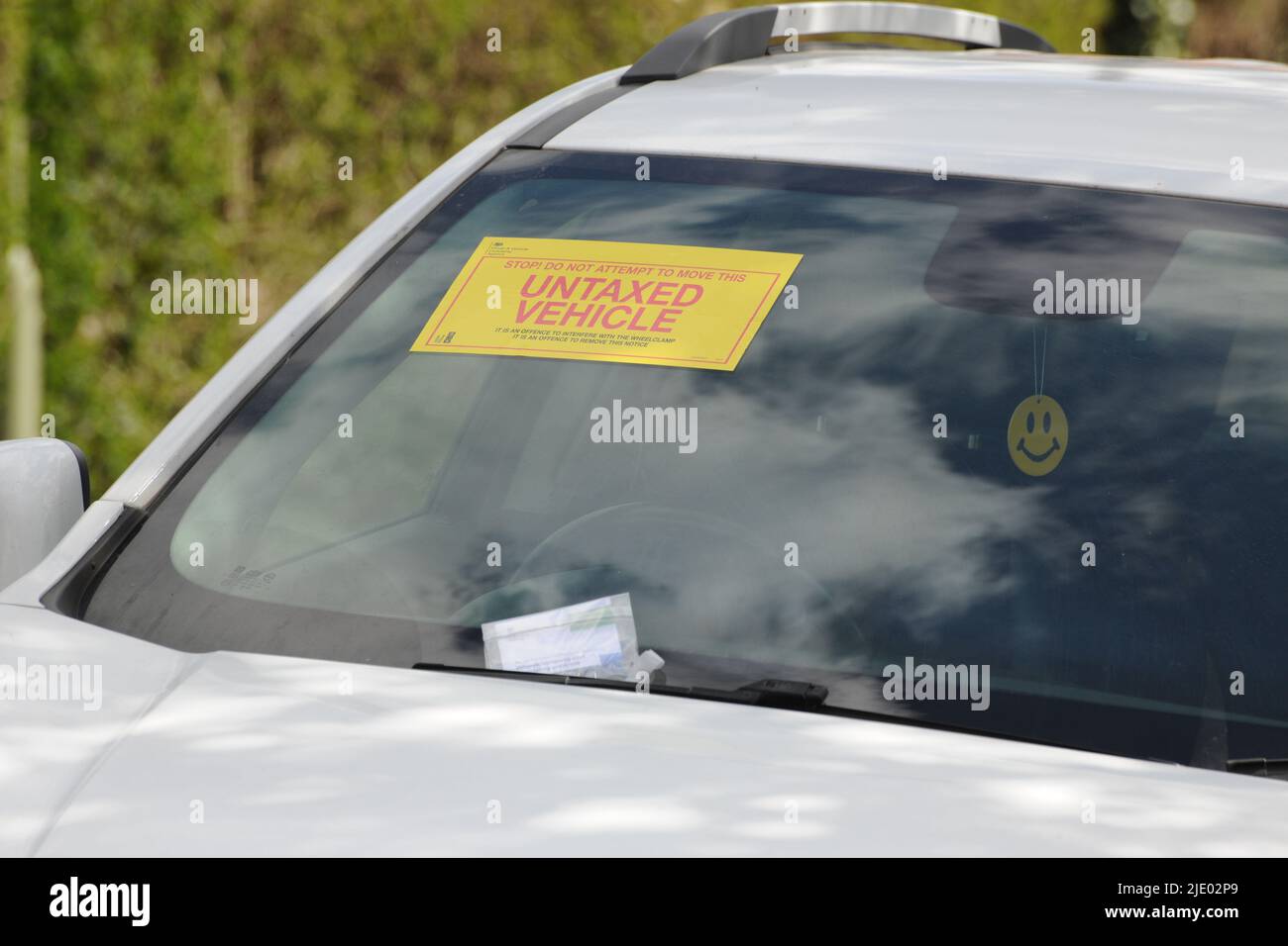 uninsured or untaxed vehicle clamped by roadside Stock Photo