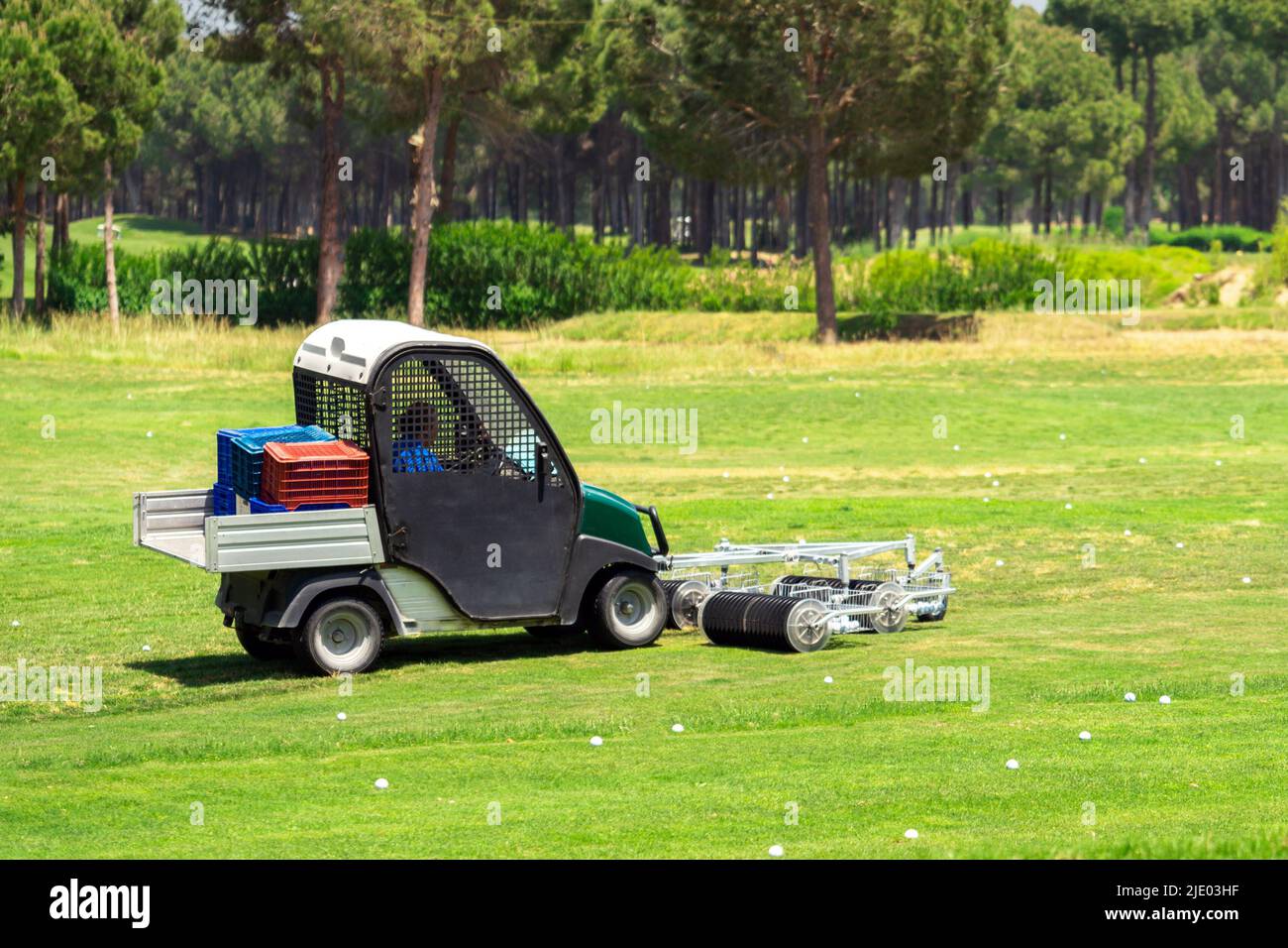 Golf course and a vehicle collecting golf balls. Ballpicker on driving