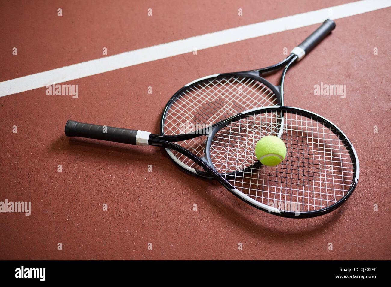 Close-up of black modern rackets with light green ball lying on tennis ...