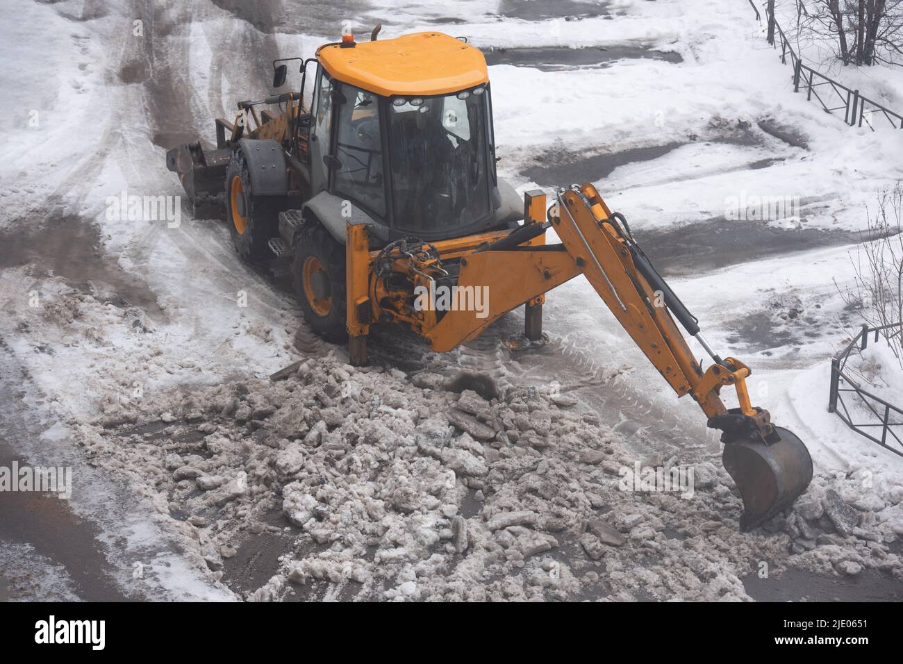 Excavator cleans street from heavy ice Stock Photo