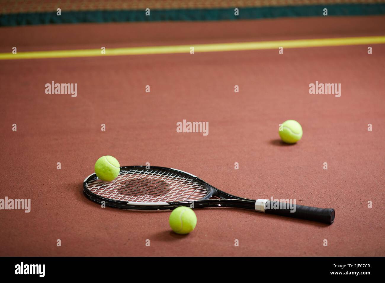 Closeup of modern tennis equipment scattered on floor of indoor tennis court, background of