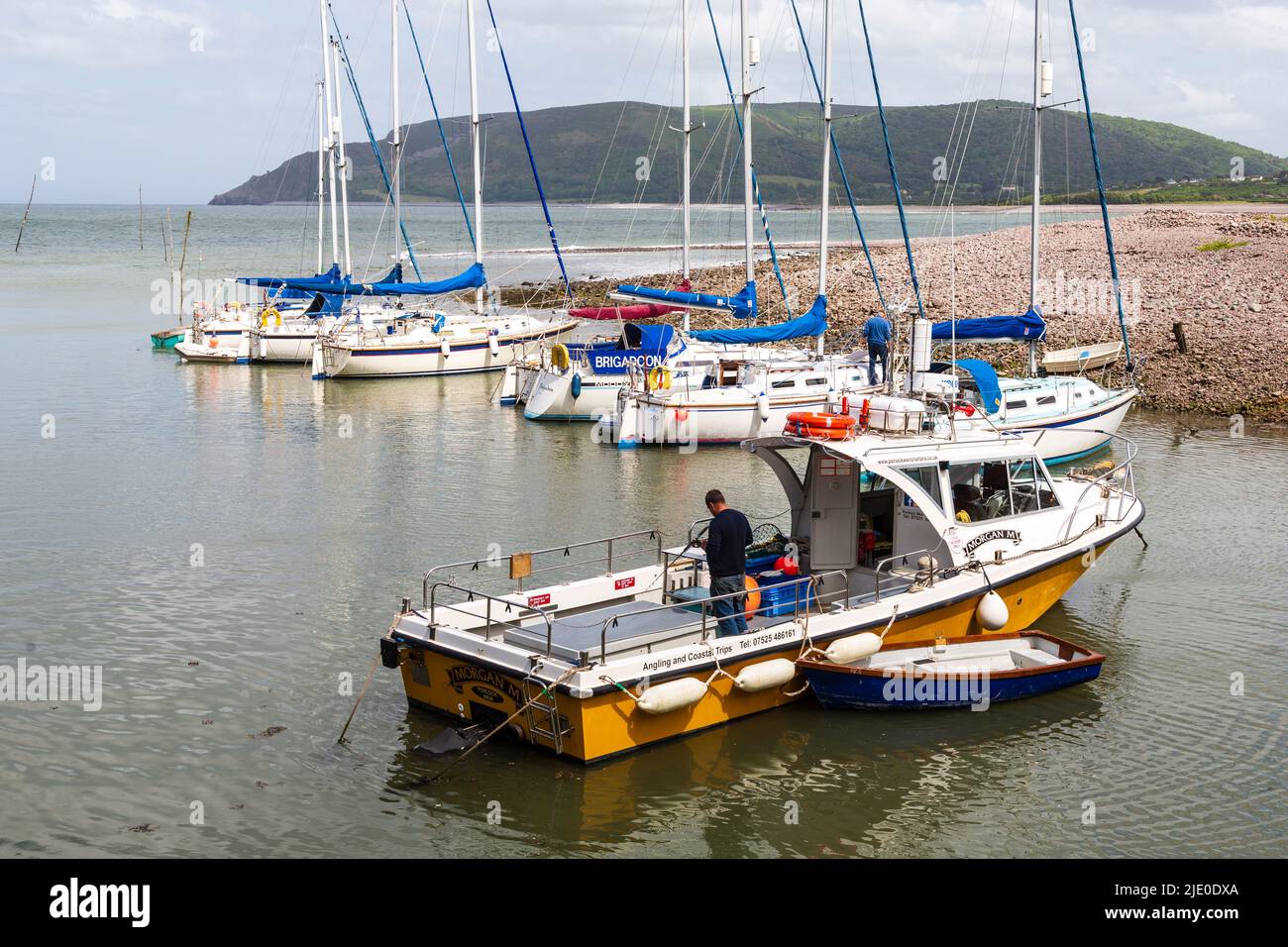 Porlock Weir,  a small port in the Exmoor National Park, Somerset, England. The harbour, with sailing boats moored up, including aan angling boat. Stock Photo