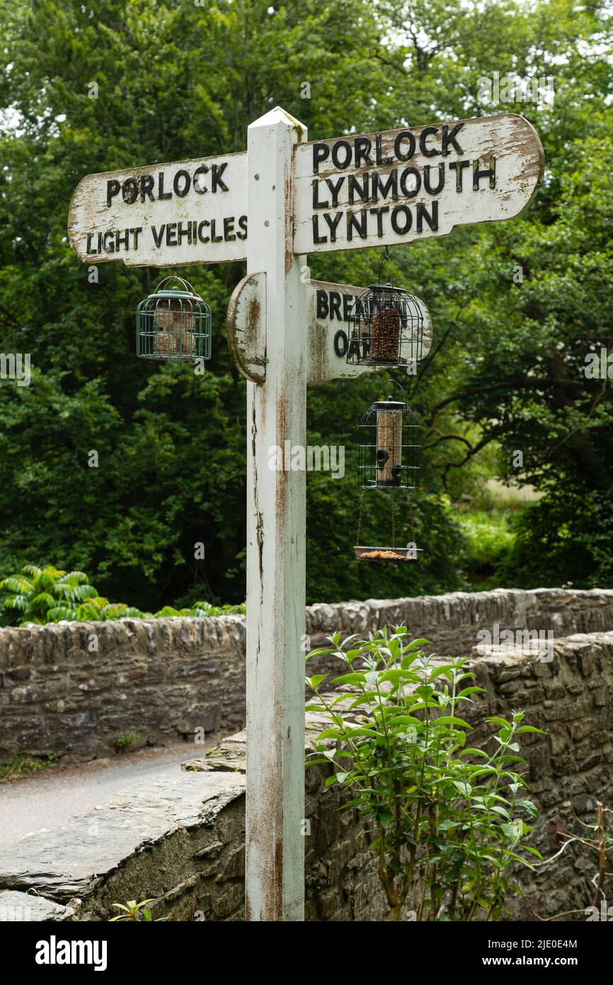 Finger style signpost in Exmoor National Park, Somerset, hung with bird feeders. Stock Photo