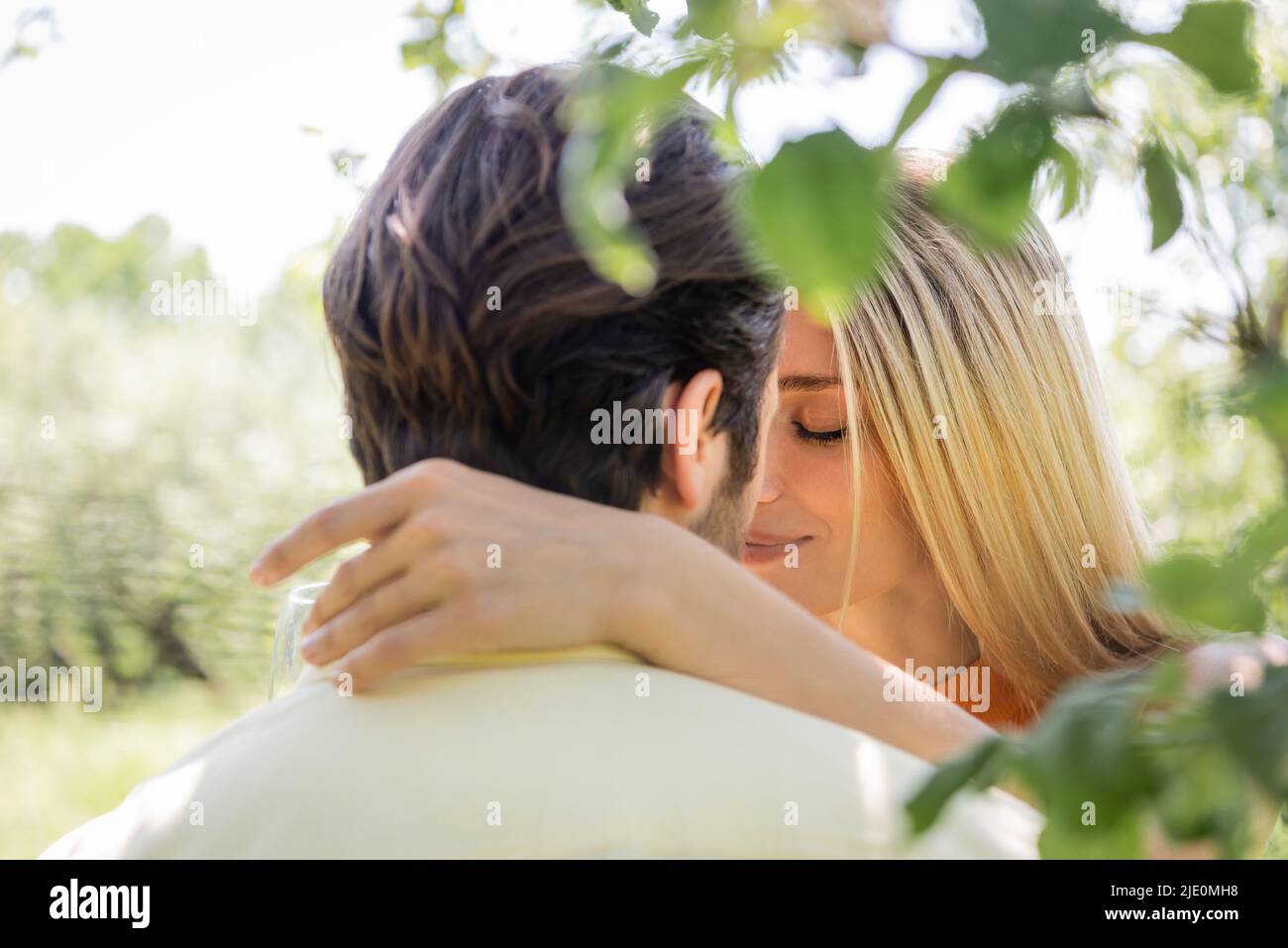 Woman kissing and hugging blurred boyfriend in summer park Stock Photo ...