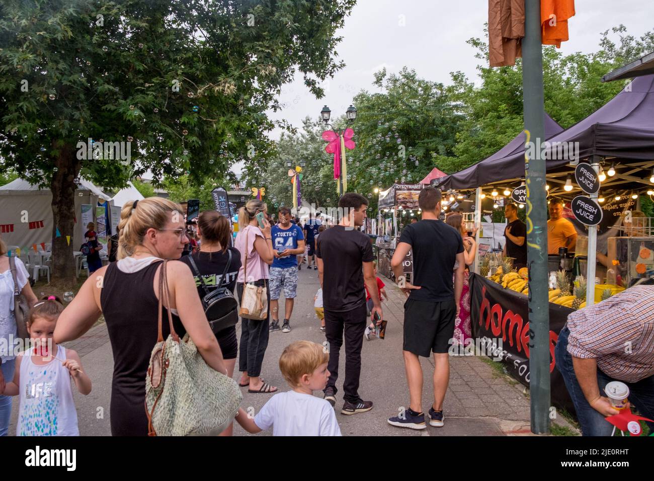 People walking on the sidewalk and buying from the food stands during a festival Stock Photo