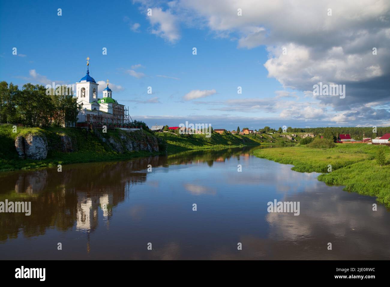 an old Orthodox church and a village on the river bank.sun , blue sky ...