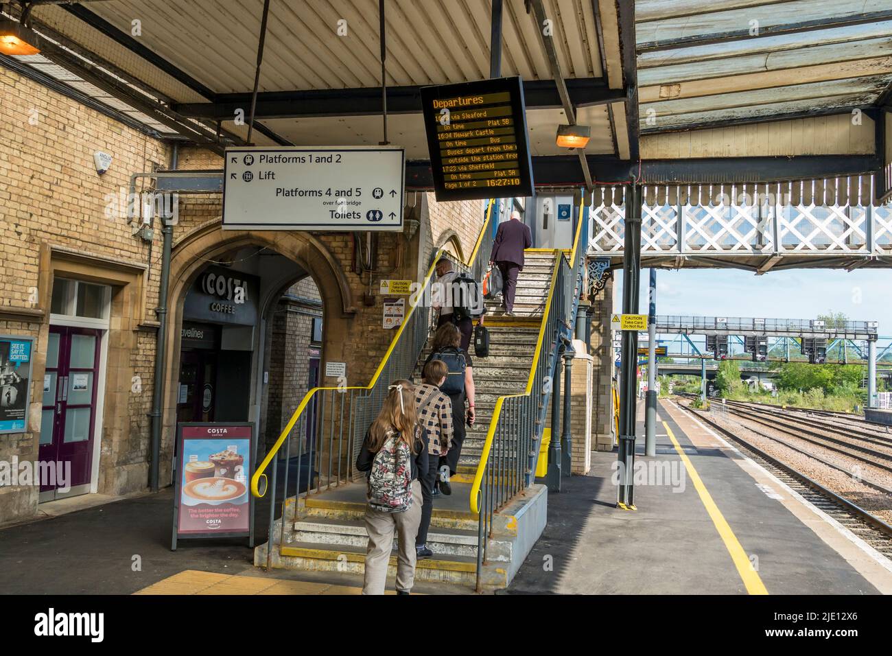 Passengers heading upstairs to cross railway lines by overhead bridge Lincoln station 2022 Stock Photo