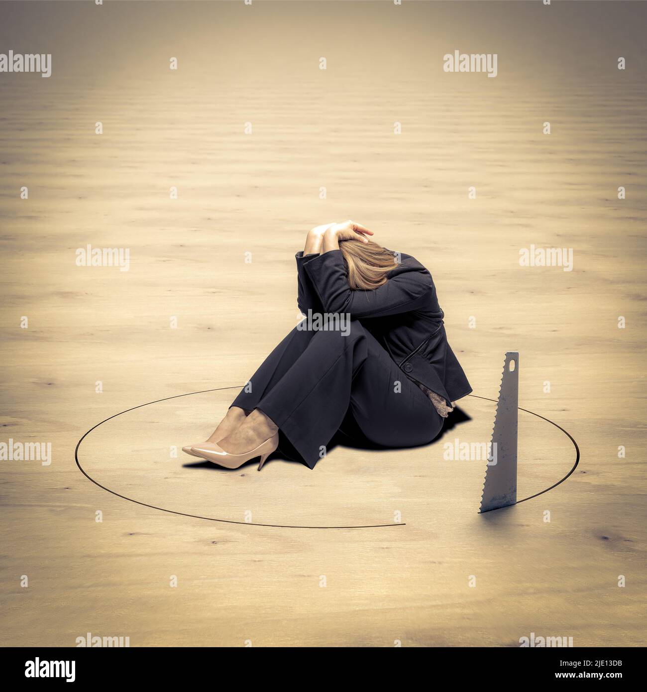 desperate woman sitting on the ground and saw trying to cut a hole to make it fall. Stock Photo