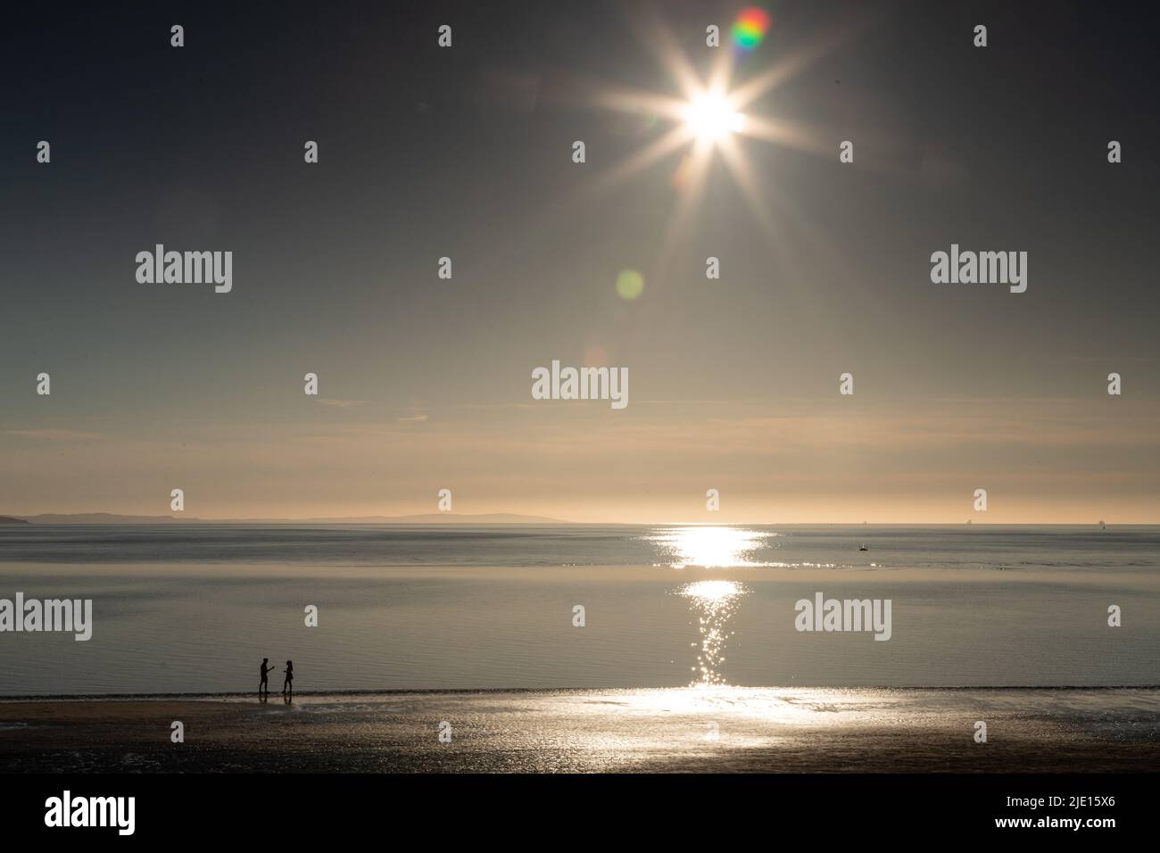 Sun and couple on the West Shore beach, Llandudno, North Wales Stock Photo