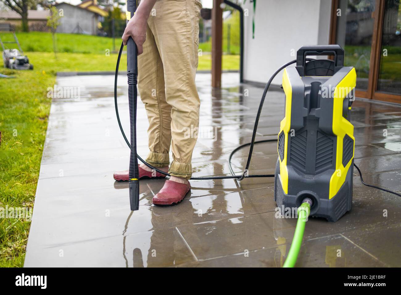 Pressure washer cleaning machine on wet concrete floor near the house