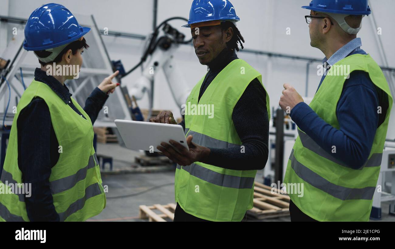 Team of engineers working in robotic factory monitoring the project on the tablet - Tech industry concept Stock Photo
