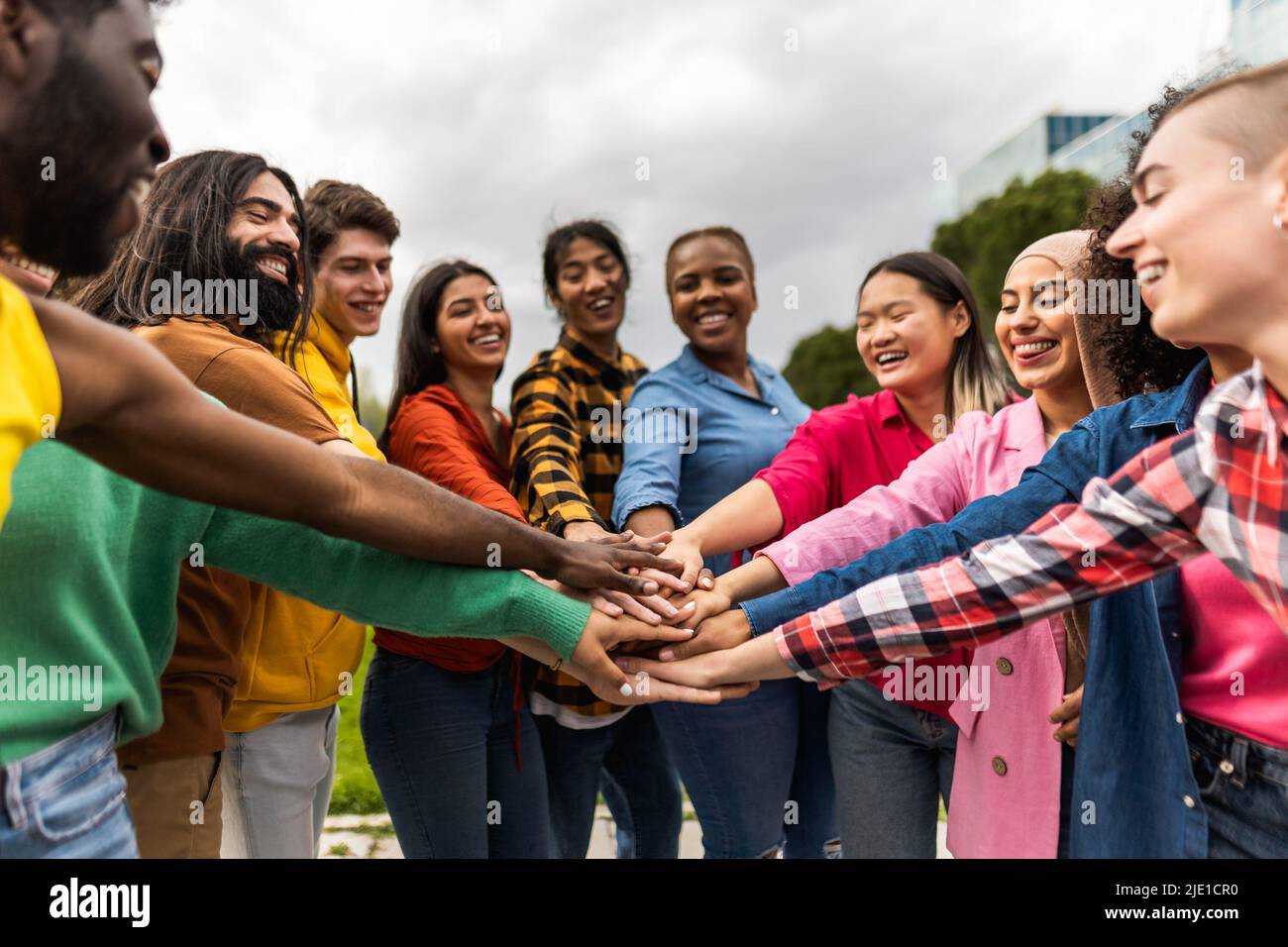 Young multiracial community of friends having fun stacking hands together outdoor - Friendship and diversity concept Stock Photo