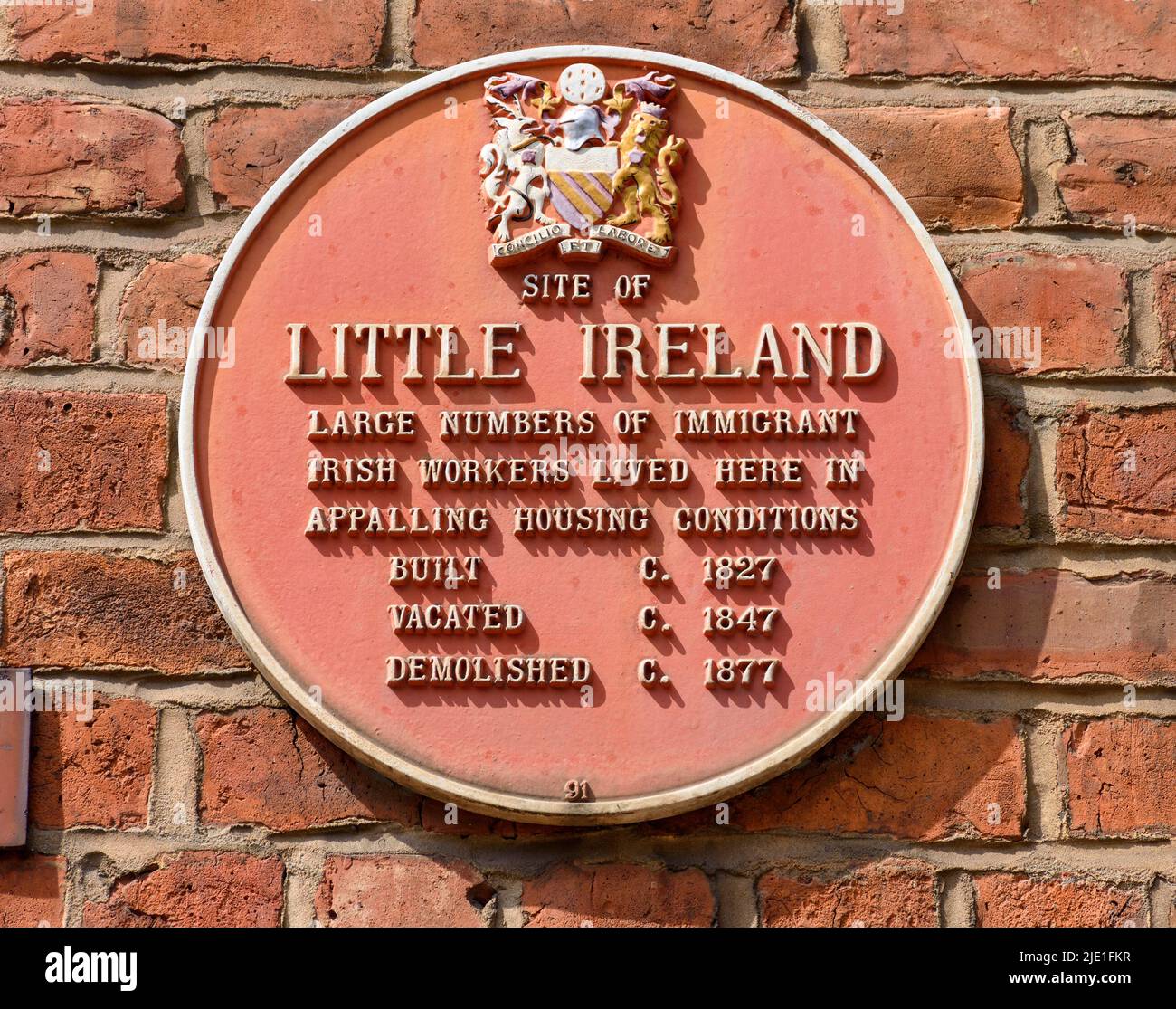 Red plaque commemorating the site of the former slum area known as Little Ireland.  On No.8 Great Marlborough Street, Manchester, UK. Stock Photo