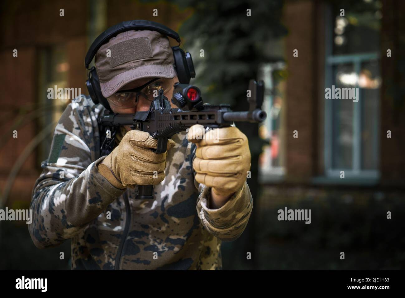 Tactical training course young man. Outdoor shooting range. Shotgun weapon action course. Private military contractor at tactical training course. Shooter with a gun in military uniform. Stock Photo