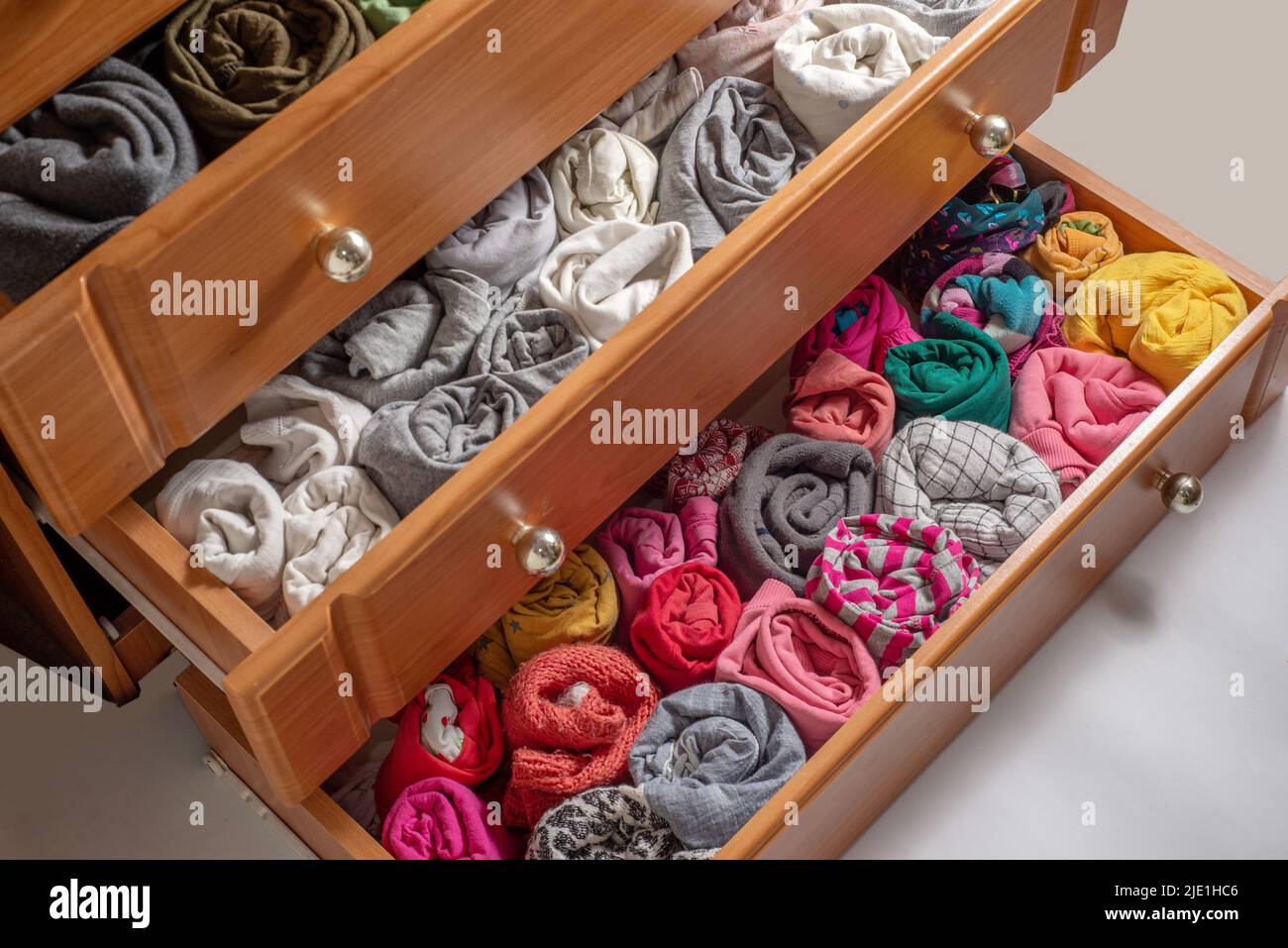 Open chest drawers with vertical storaged twisting clothes. View from