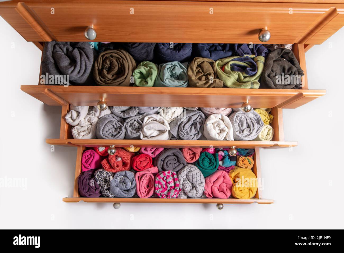 Open chest drawers with vertical storaged twisting clothes. View from