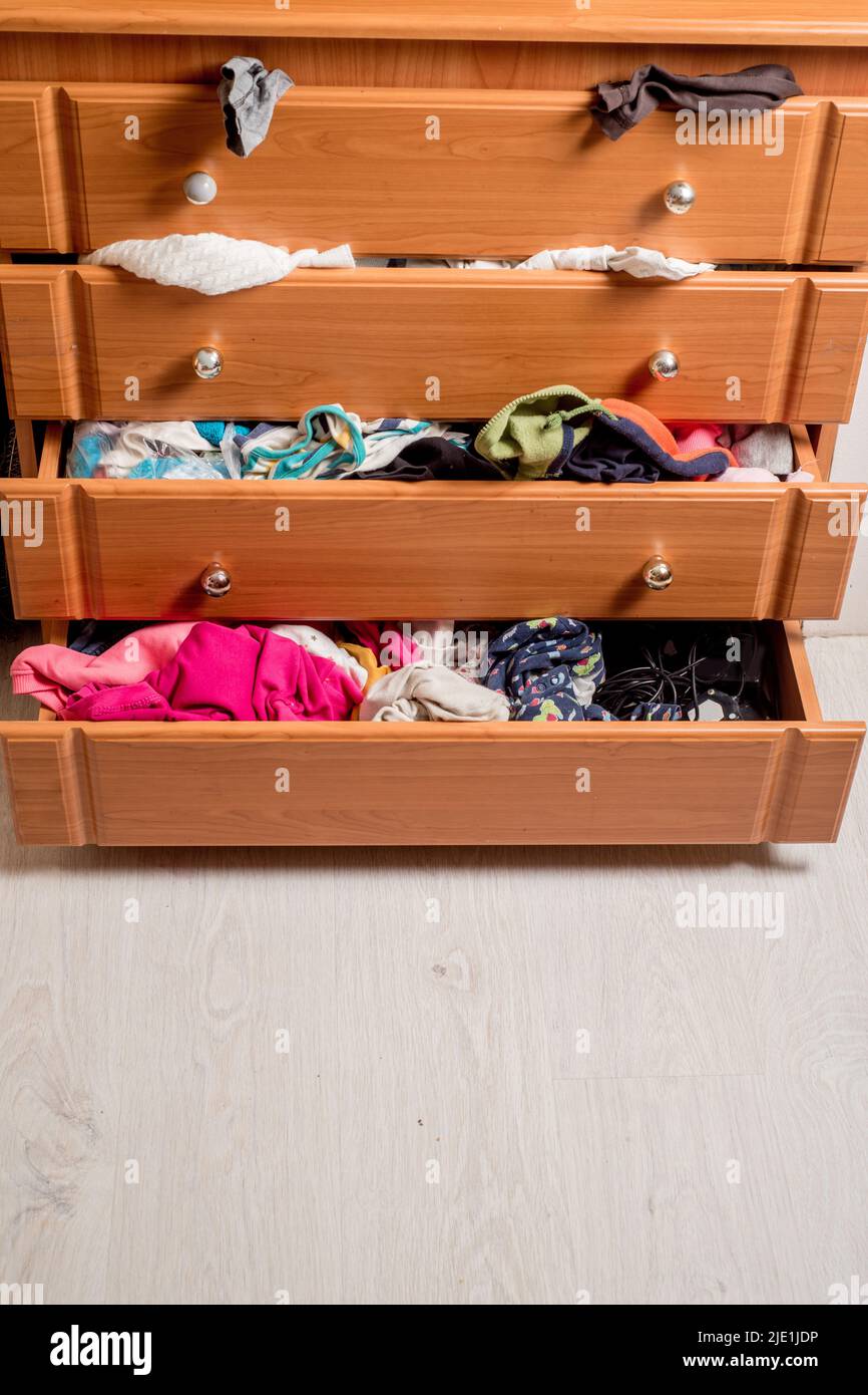 open chest drawers with dropdown clothes and piles of clothes around