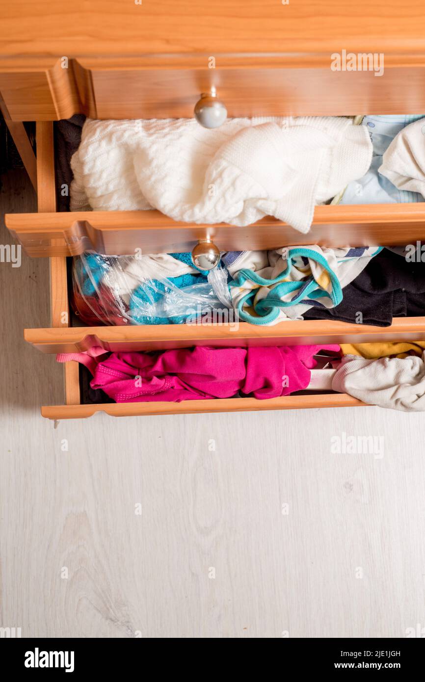 open chest drawers with sticking out randomly clothes.View from above