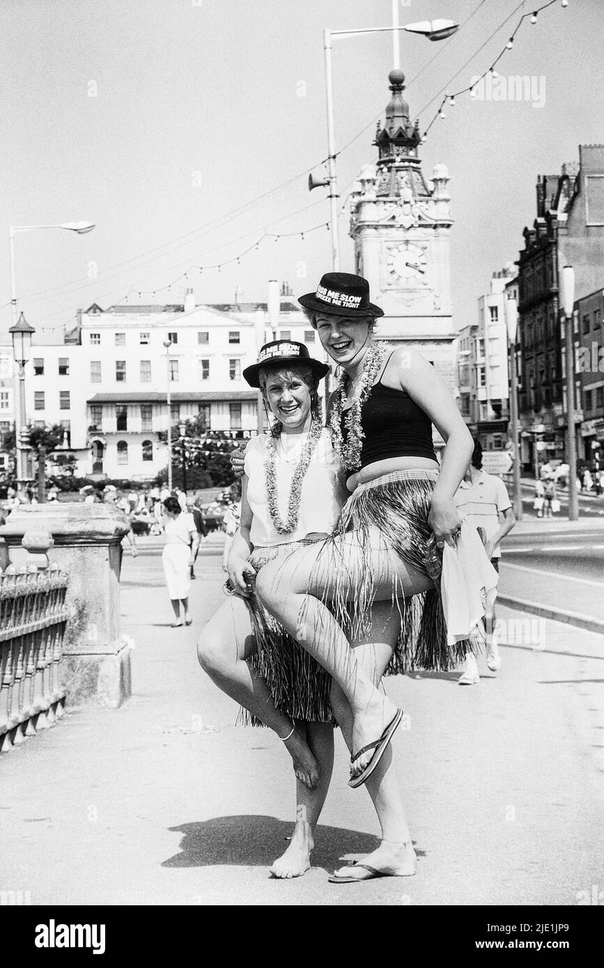 Young women in fancy dress. British seaside novelty hat, typically bearing the words 'Kiss me quick' or 'Kiss me quick, squeeze me slow' Margate, Kent, England, UK. Circa 1980's Stock Photo