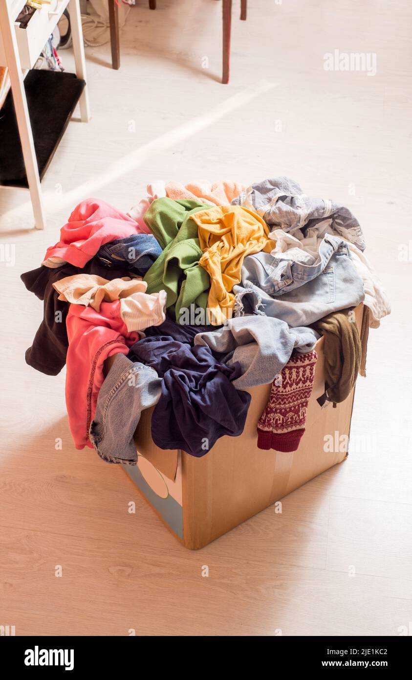 Pile of clothes in a large cardboard box. Decluttering the wardrobe