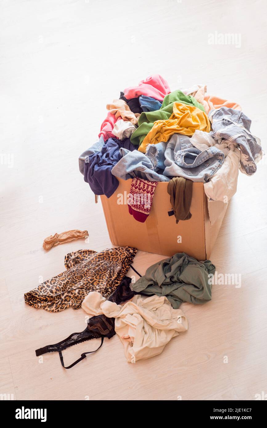 Pile of clothes in a large cardboard box. Decluttering the wardrobe