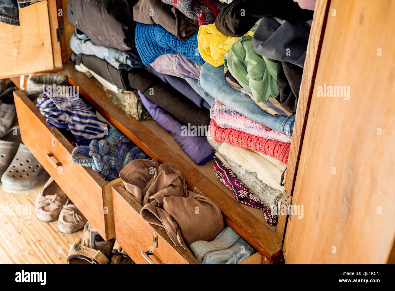 Old clothes and shoes in an overflowing closet. Second hand reuse. Decluttering and cleaning the cabinet. Second hand reuse. Decluttering and cleaning Stock Photo