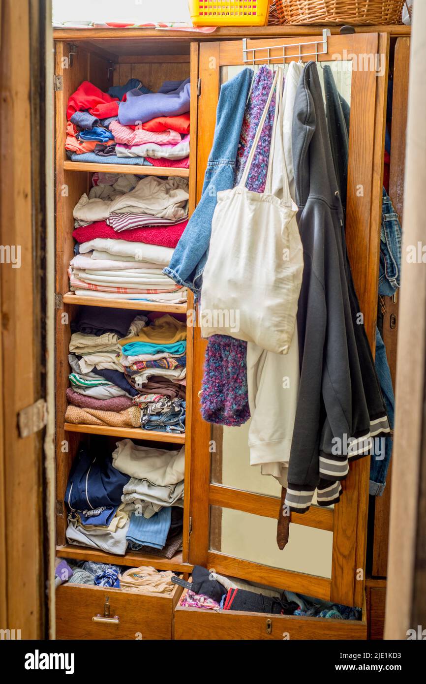 Wardrobe overflowing with clothes and things. Second hand reuse. Decluttering and cleaning the cabinet Stock Photo