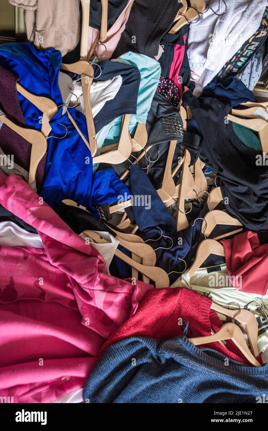 Lots of clothes on hangers piled in a pile. Cleaning the wardrobe